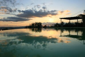 A serene outdoor pool area with a clear view of the sunset and surrounding landscape. - Il Castellaccio (Perugia)