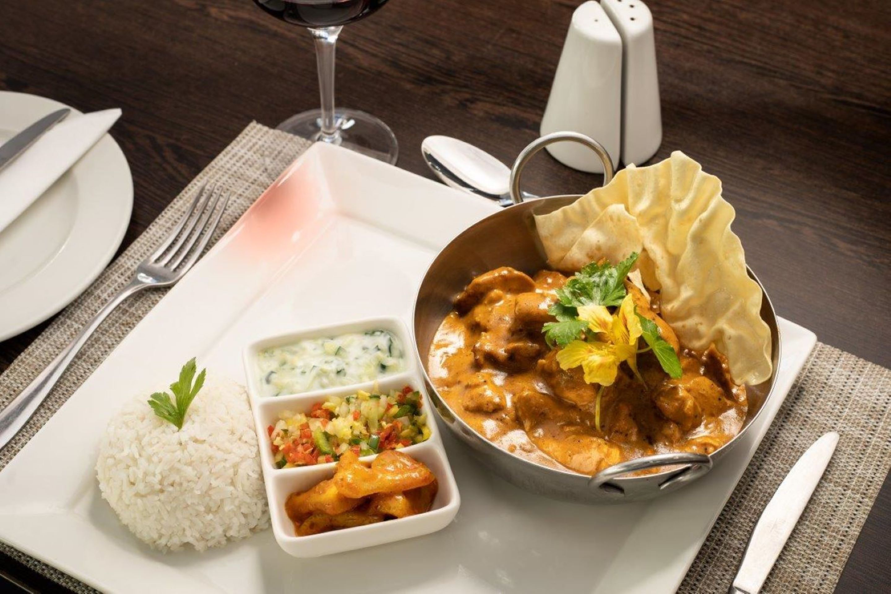 A meal with rice, a curry dish, and a side of chutney and salad.