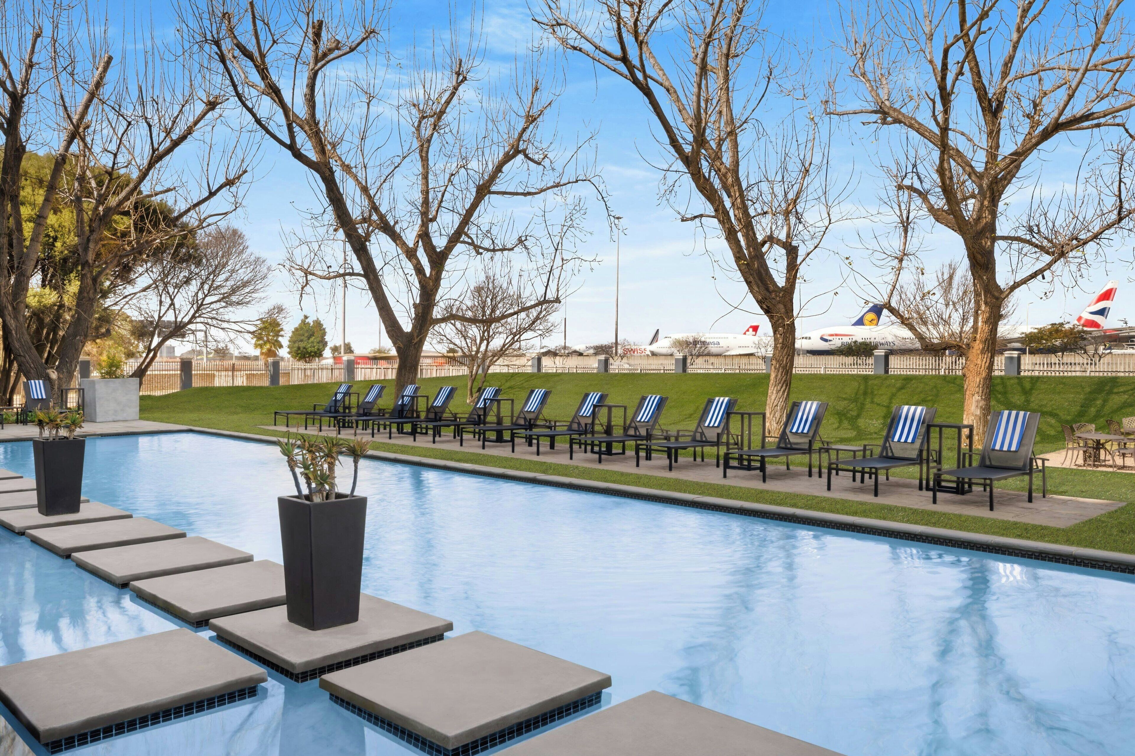 A swimming pool with lounge chairs and potted plants.