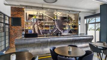 A modern bar area with a curved counter, seating arrangements, and a view of the outdoors.