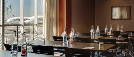 A hotel conference room with tables, chairs, and water bottles.
