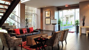 A modern lobby with a staircase, a leather sofa, patterned chairs, a wooden coffee table, and framed artwork on the walls. - Protea Hotel by Marriott O.R. Tambo Airport (Kempton Park)