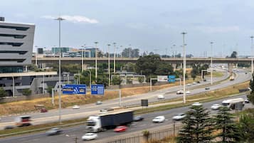 A multi-lane highway with vehicles, overhead signs, and modern buildings in the background.