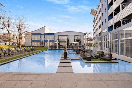 Una piscina al aire libre, sombrillas, sillones reclinables de piscina