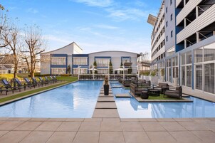 Una piscina al aire libre, sombrillas, sillones reclinables de piscina