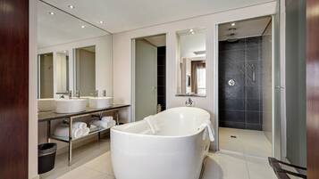 A modern bathroom with a freestanding bathtub, dual sinks, and a walk-in shower.