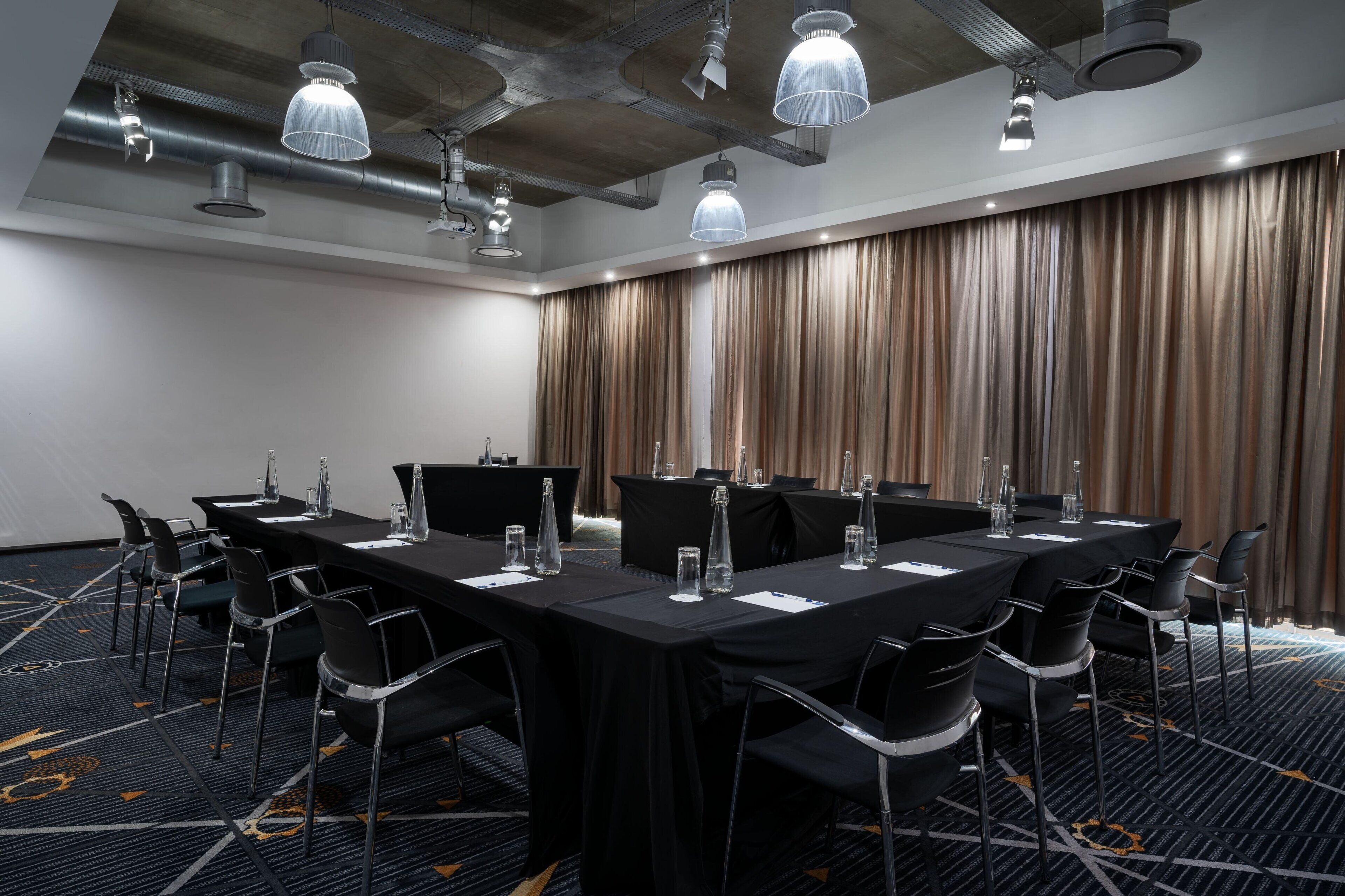 A conference room with a long table, black chairs, and a curtain backdrop.