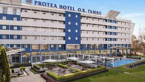 A hotel with a pool, outdoor seating, and a well-maintained garden. - Protea Hotel by Marriott O.R. Tambo Airport (Kempton Park)