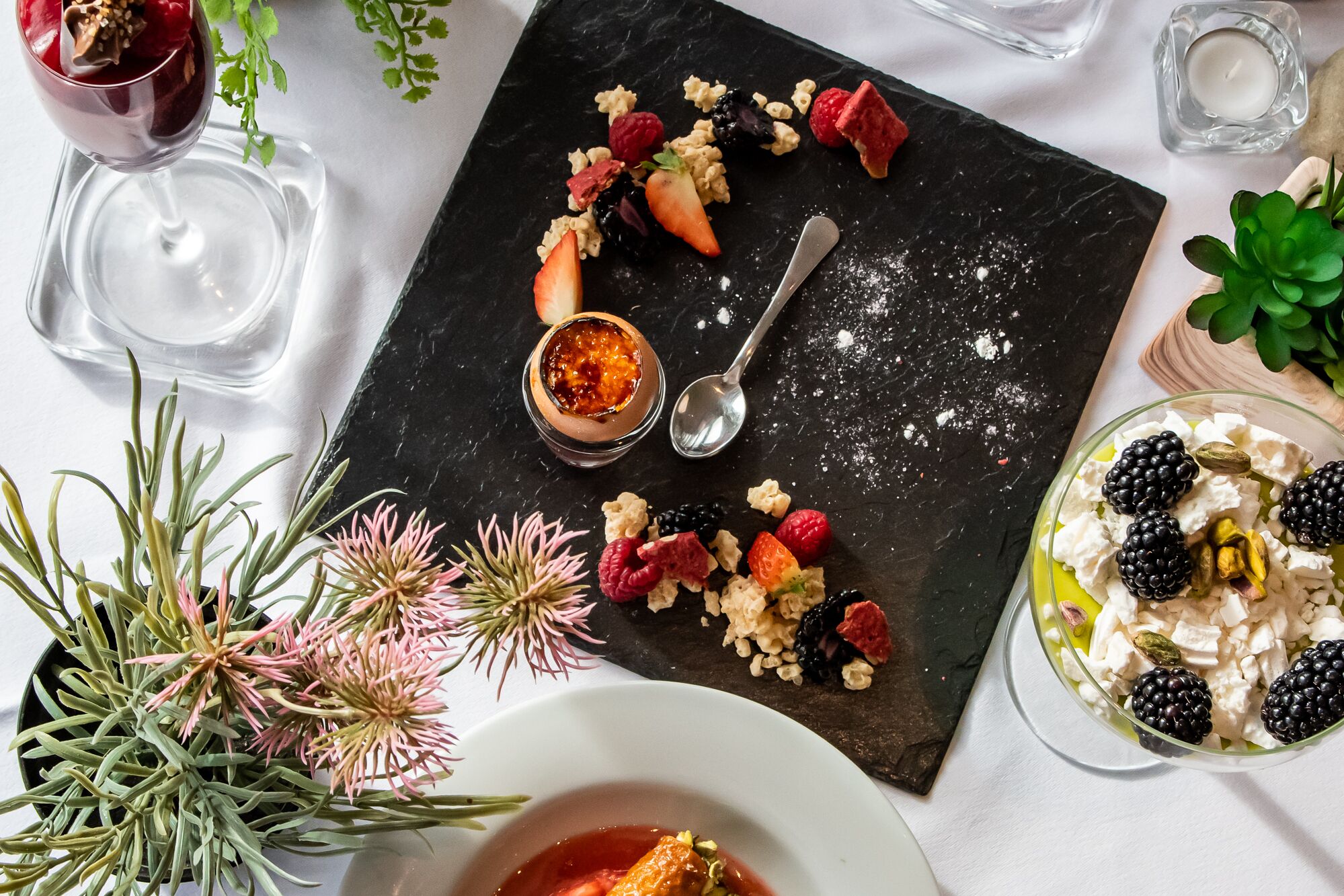Una mesa de postres con diversas frutas, nueces y un recipiente pequeño de mermelada.
