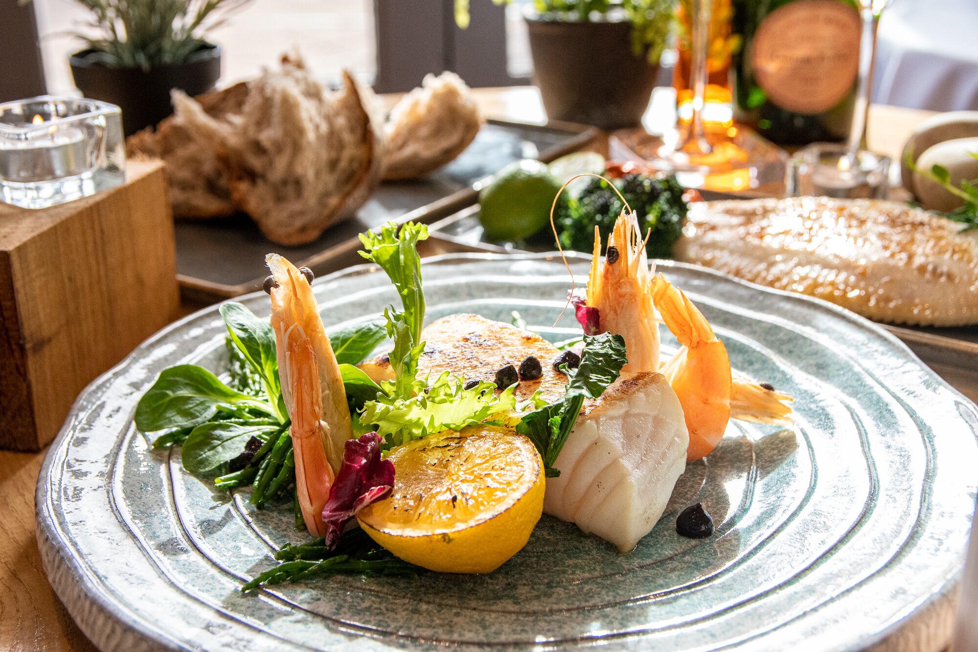 A plate of food with shrimp, fish, and vegetables on a ceramic plate.