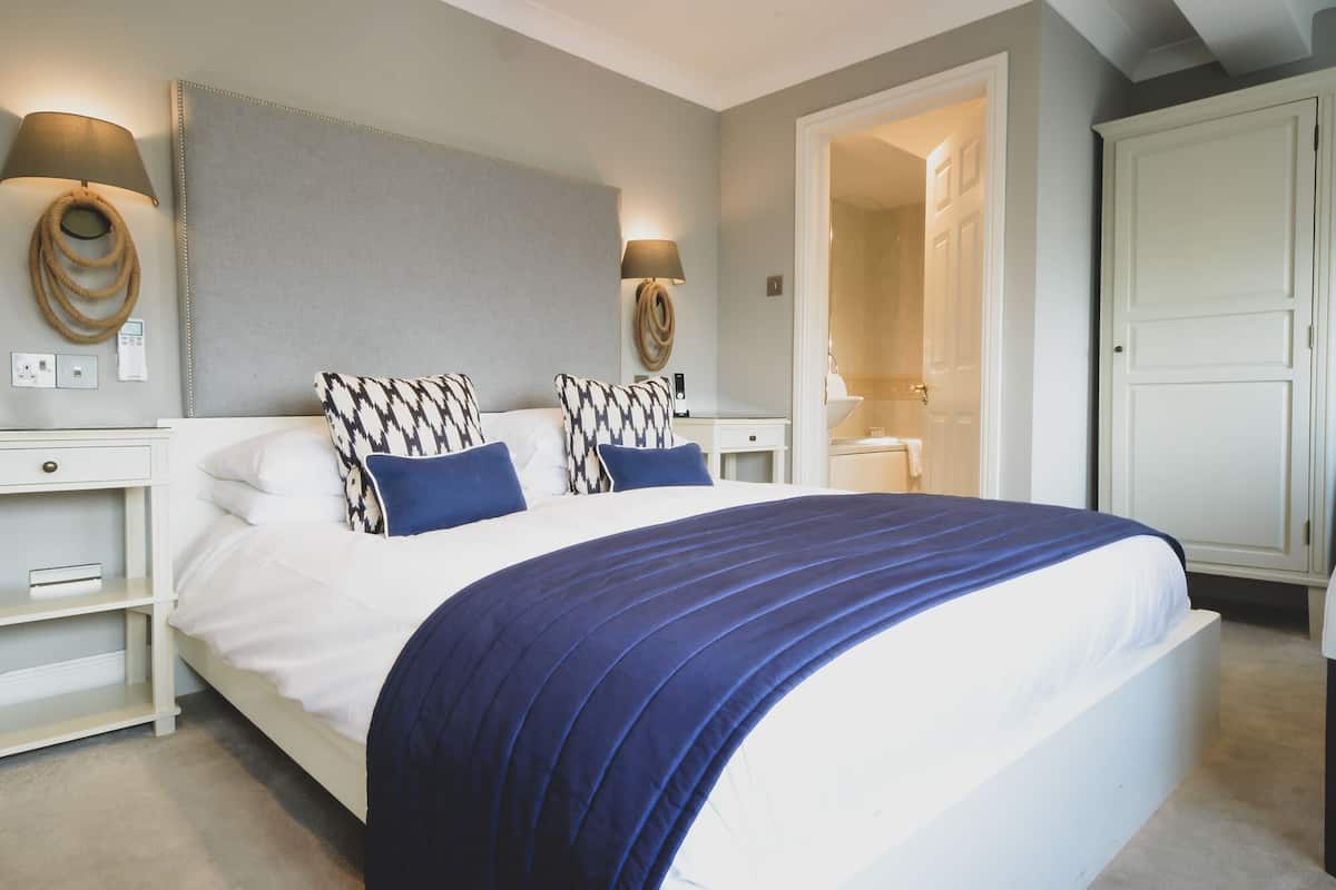 A neatly arranged bedroom with a large bed, two bedside lamps, a headboard, and a wardrobe.