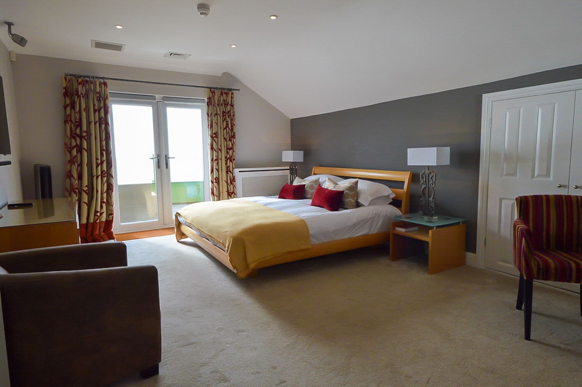Een hotelkamer met een bed, een stoel, een bureau en een deur.