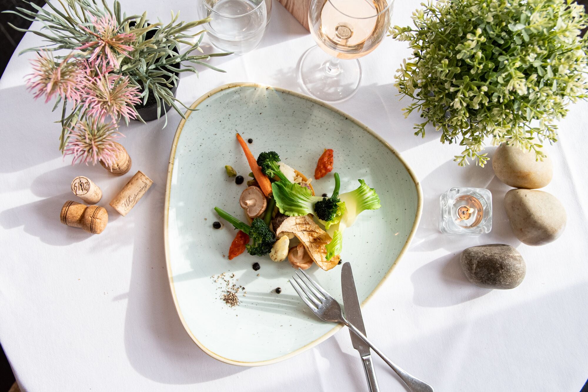 Una mesa de comedor con un plato de comida, una copa de vino, una vela y adornos decorativos.