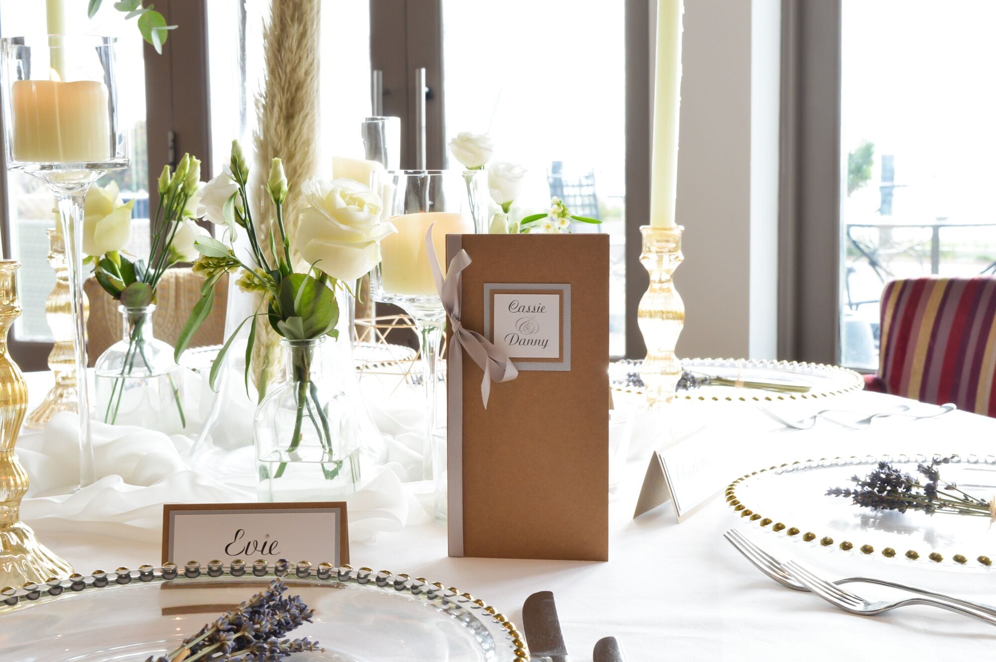 Een gedekte tafel voor een formeel evenement, met plaatskaarten, een bruin kaartje met een lint en bloemdecoraties.