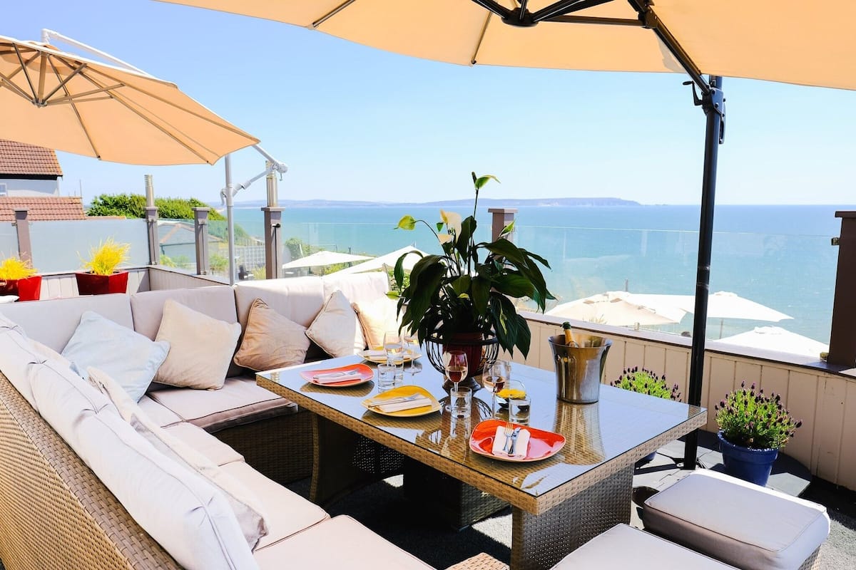 An outdoor seating area with a table set for dining, a sofa, and a potted plant.