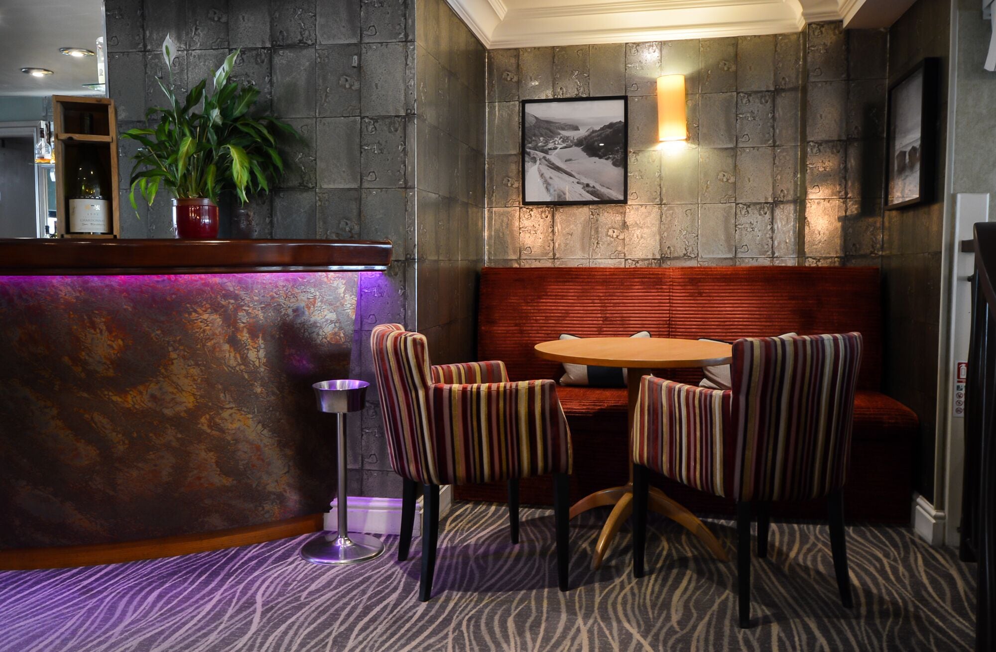 Een restaurant met een stenen muur, een houten toonbank, gestreepte stoelen en een ronde tafel.