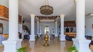 A spacious lobby with high ceilings, white columns, a central chandelier, and a staircase leading to an upper level. - Daniela Village Dahab (Dahab)
