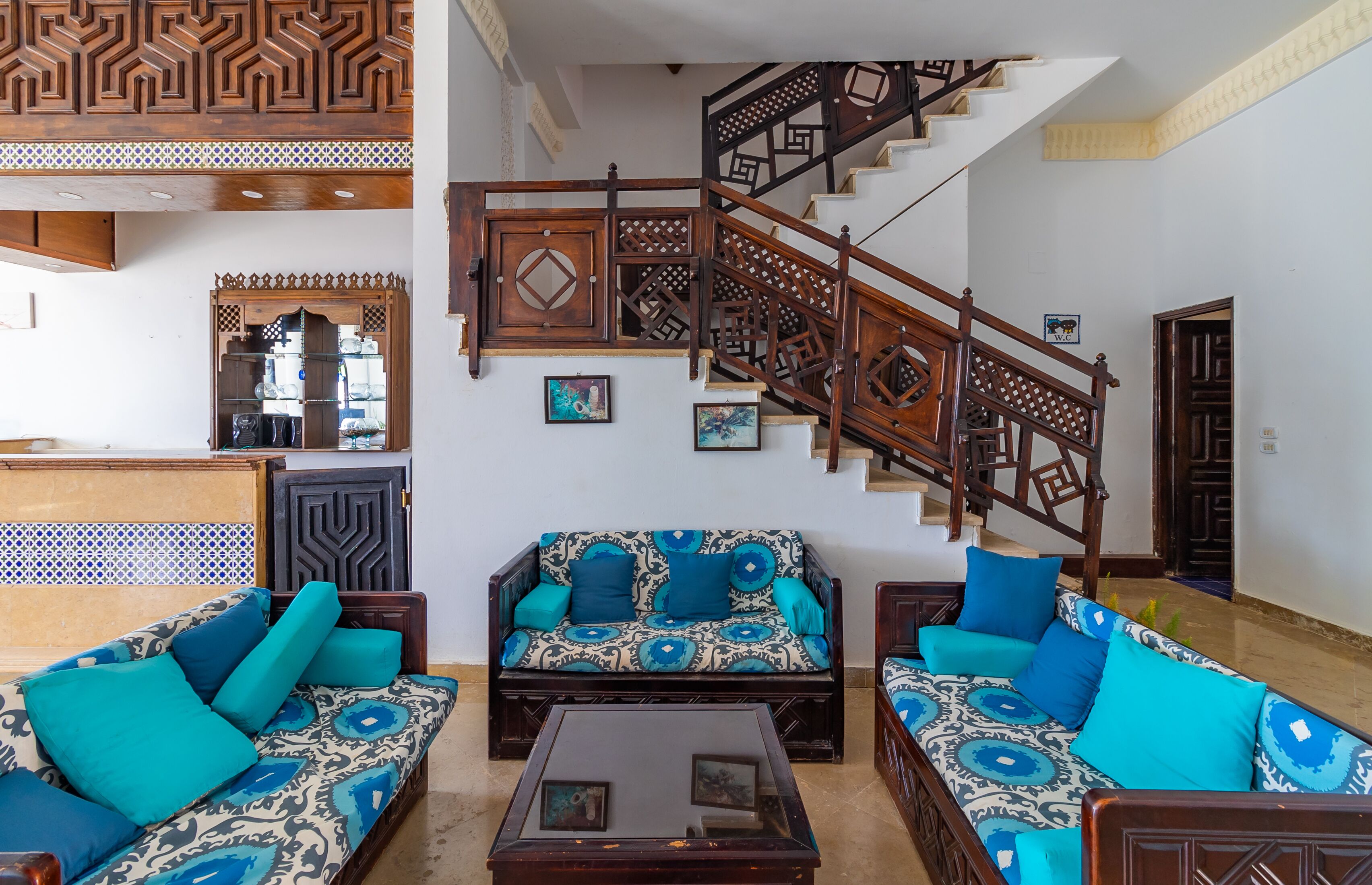 A spacious living area with a sofa set, a coffee table, and a wooden staircase.