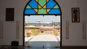 A doorway leading to a pool area with umbrellas and lounge chairs. - Daniela Village Dahab (Dahab)