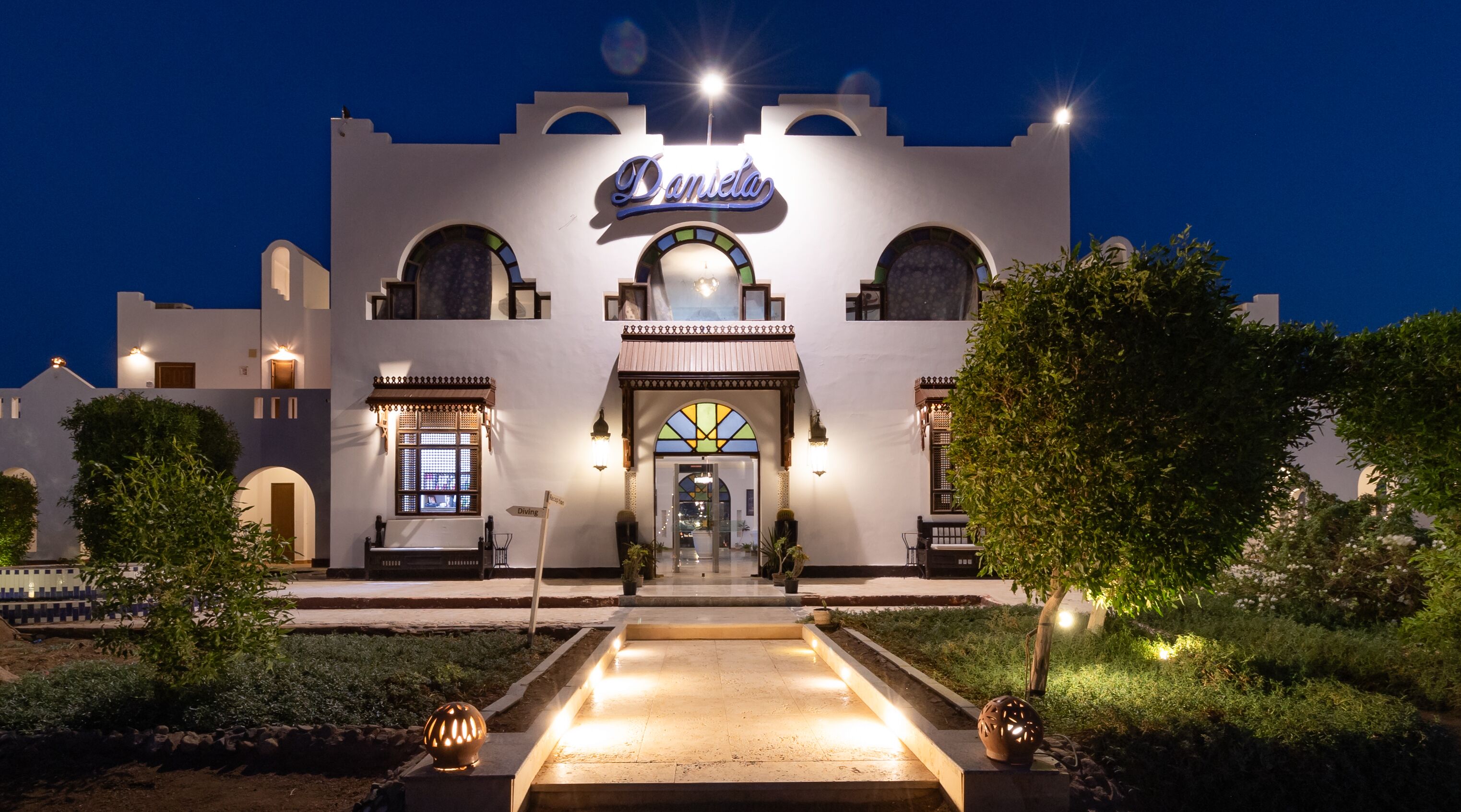 A hotel with a prominent sign reading "Daneta," featuring a traditional architectural style with arched windows and a central entrance.