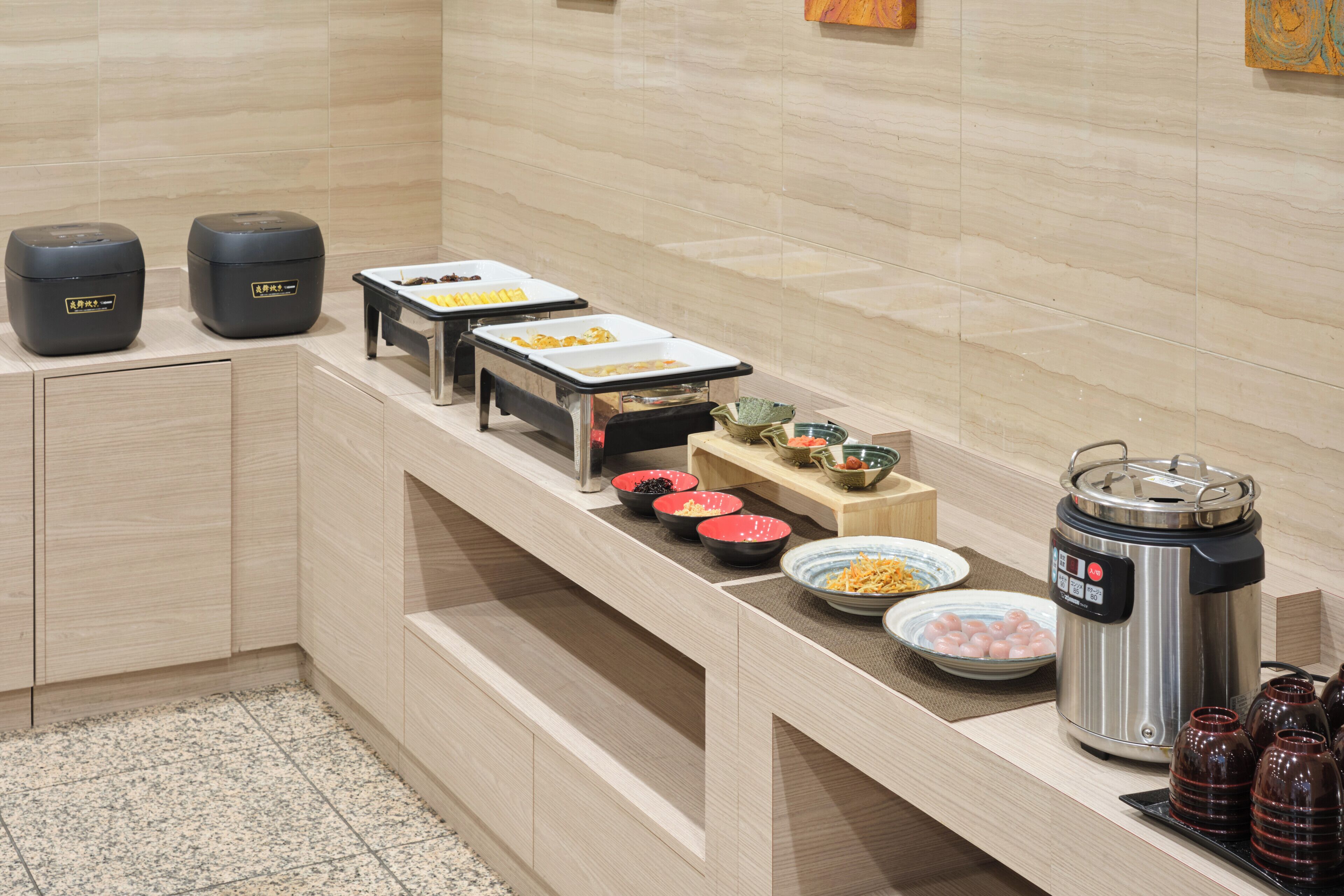 A buffet setup with various food items, a coffee machine, and a water dispenser.