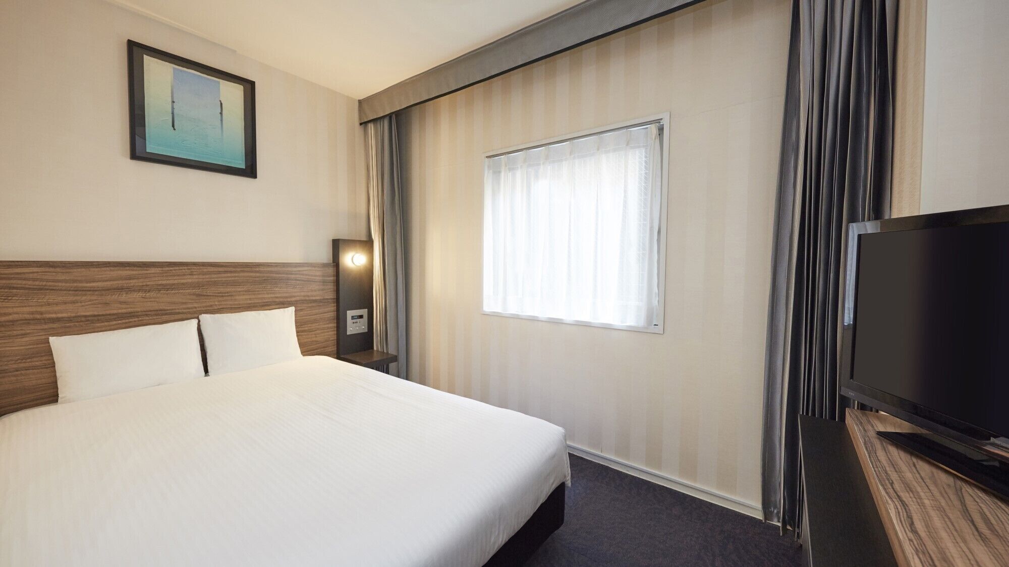 A hotel room with a large bed, a television, a window with curtains, and a painting on the wall.