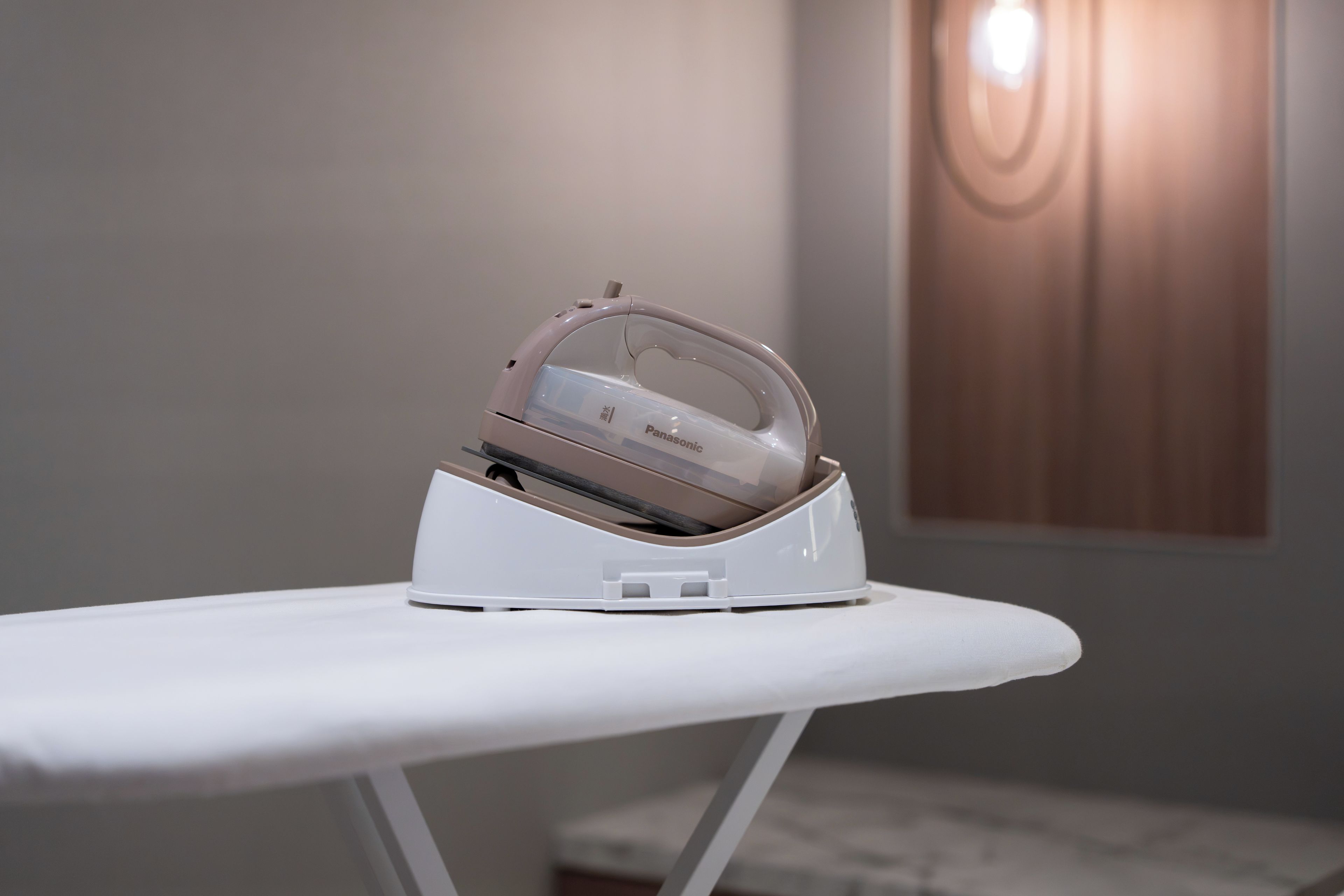 A white ironing board with a Panasonic iron on it.