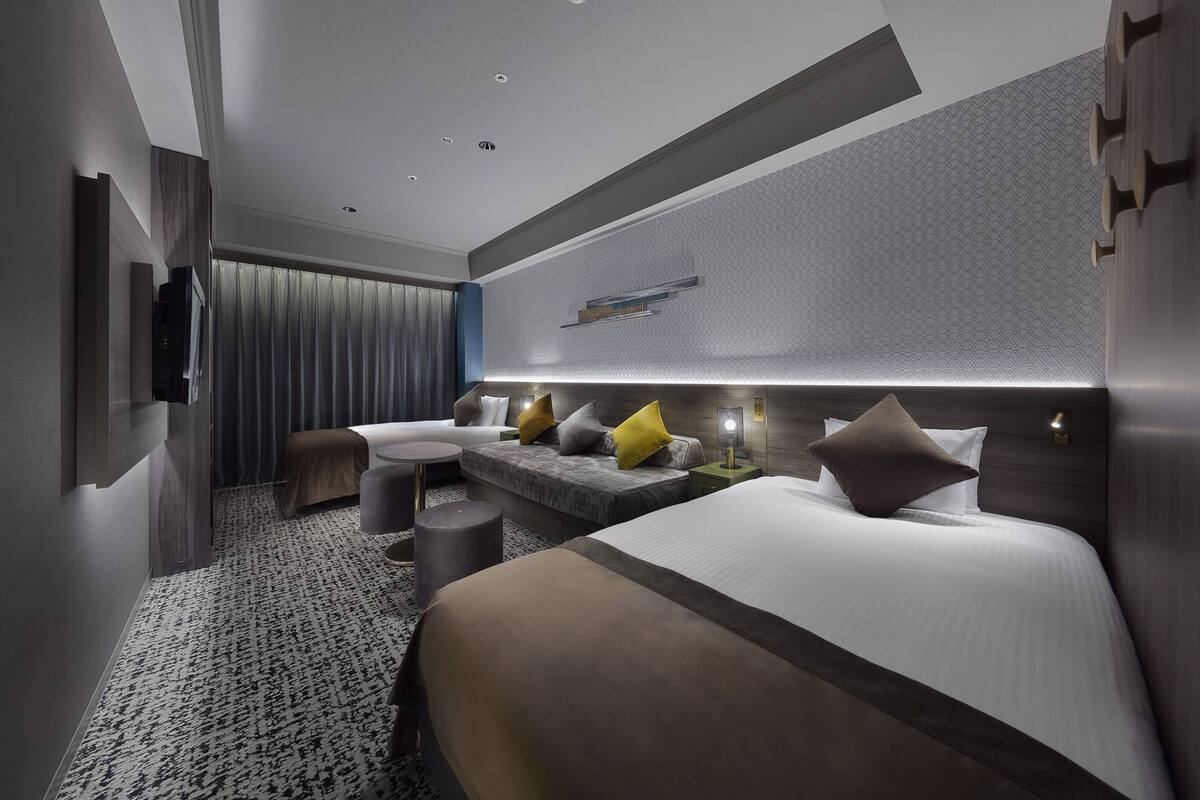 Une chambre d’hôtel moderne, dotée d  ’un grand lit, d’un canapé, d’une petite table et d’un téléviseur fixé au mur.