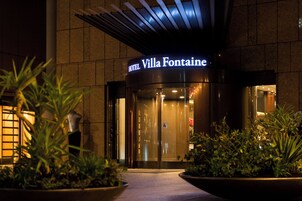 The entrance of the Villa Fontaine hotel with a glass door and a sign above it.