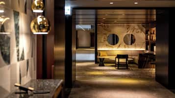 A modern interior with a reception desk, a seating area with a sofa and chairs, and a wall with circular mirrors.