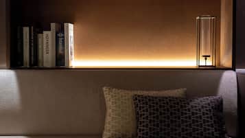 Une bibliothèque remplie de livres, une lampe et deux coussins sur un canapé.