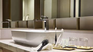 A modern bathroom with a large sink, a mirror, and toiletries on the counter.