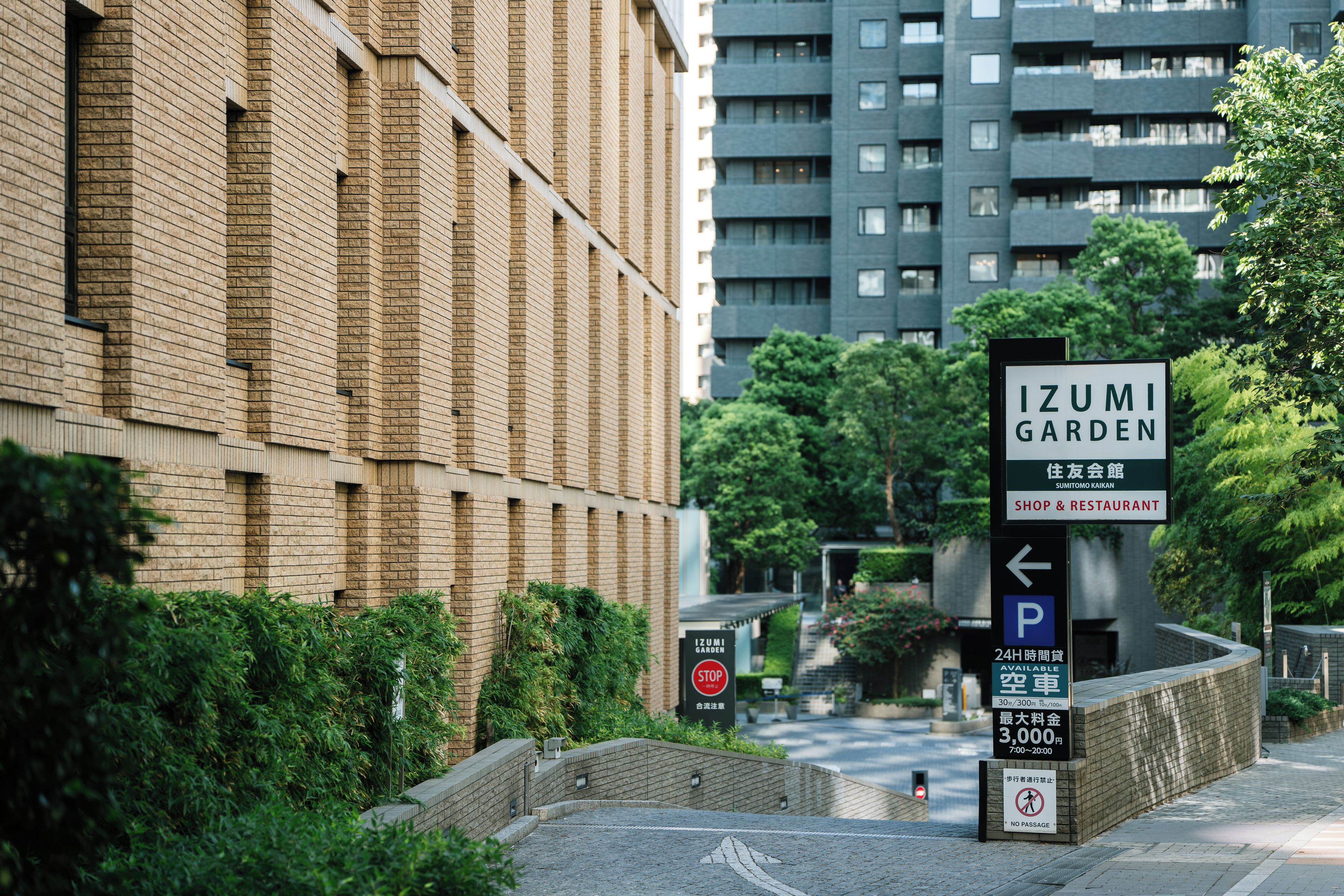 A sign for Izumi Garden with a parking area and a stop sign nearby.