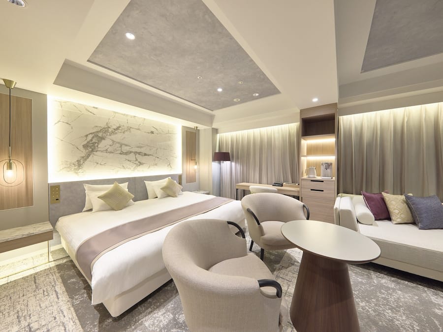 Una habitación de hotel moderna con una cama grande, un sofá, un escritorio y una silla.