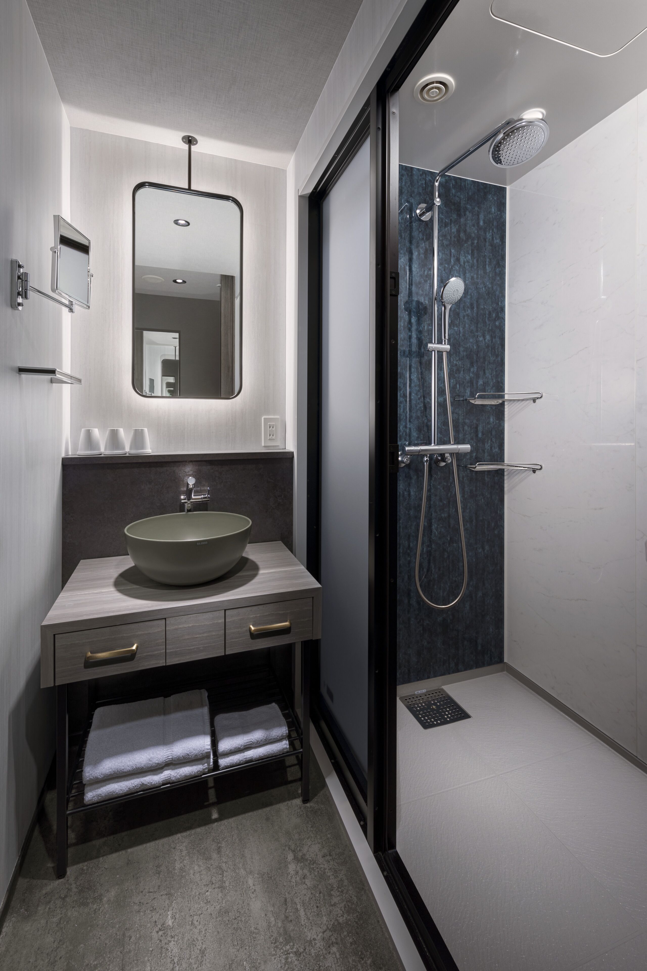 A modern bathroom with a large mirror, a vessel sink, and a walk-in shower.