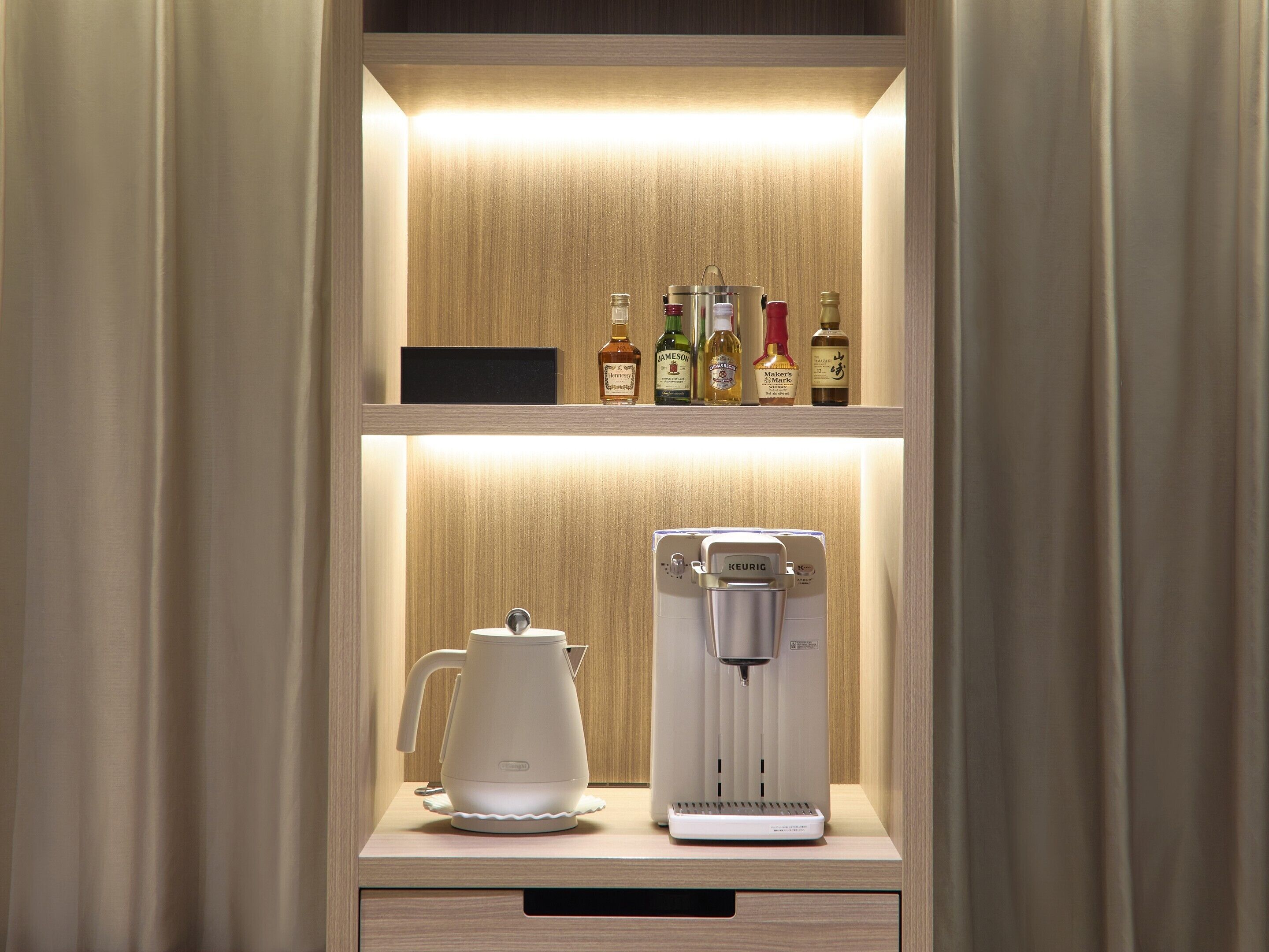 A minibar with a coffee machine and a selection of alcohol bottles.