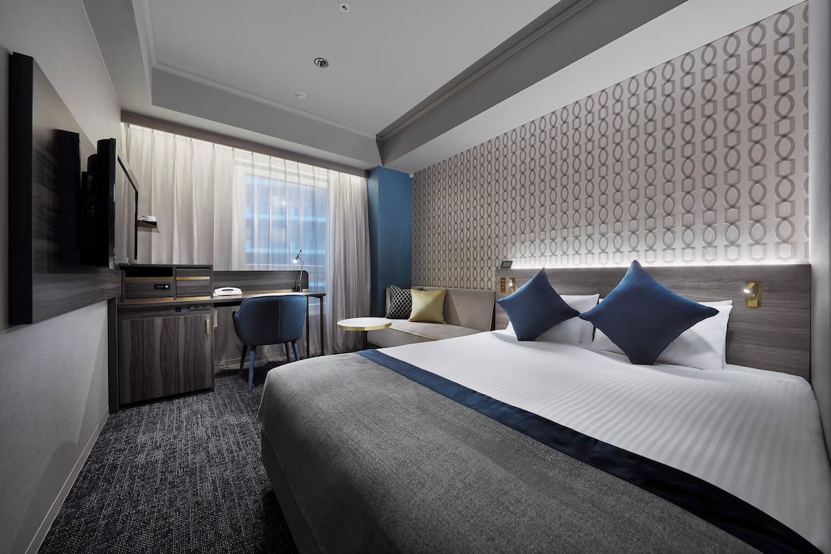 Une chambre d’hôtel avec un grand lit, un bureau, une chaise et une petite table.
