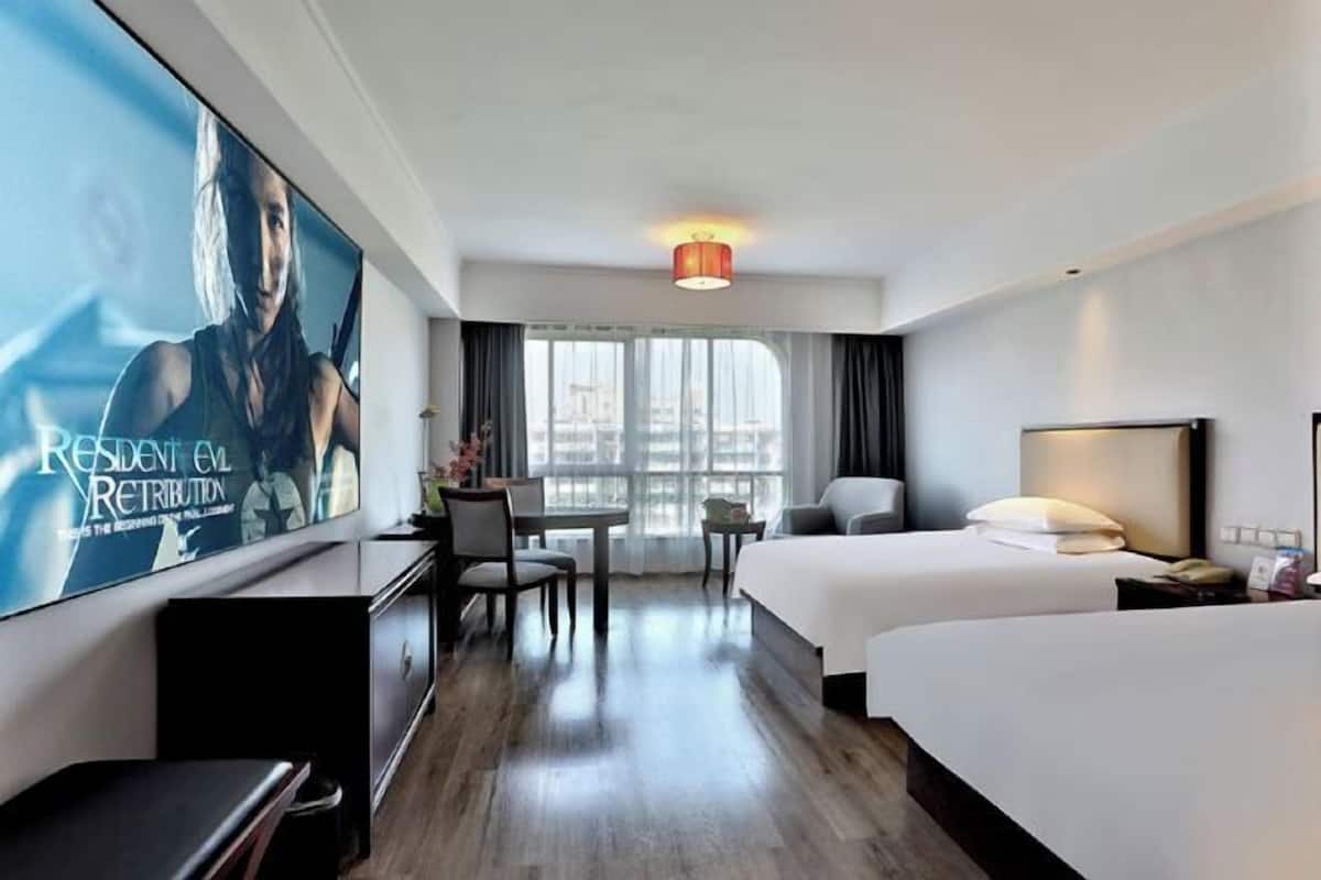 A hotel room with a bed, a desk, a chair, a TV, and a window.