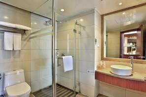 Ein modernes Badezimmer mit einer gläsernen Duschkabine, einer weißen Toilette und einem Waschtisch mit großem Spiegel und Waschbecken.