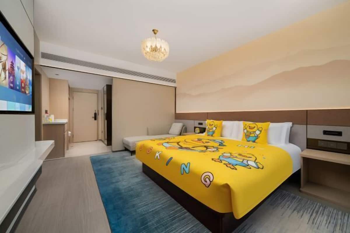 A hotel room with a bed, a television, a chandelier, and a wall with a textured design.