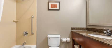 A bathroom with a bathtub, toilet, sink, and two framed pictures on the wall.
