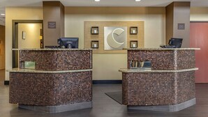 A reception area with two check-in counters, a wall-mounted C logo, and a framed picture above the counters.