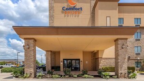 A Comfort Suites hotel entrance with a stone facade, a covered entrance area, and a clear sky.