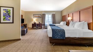 A hotel room with a large bed, a desk with a chair, a TV, and a window with curtains.