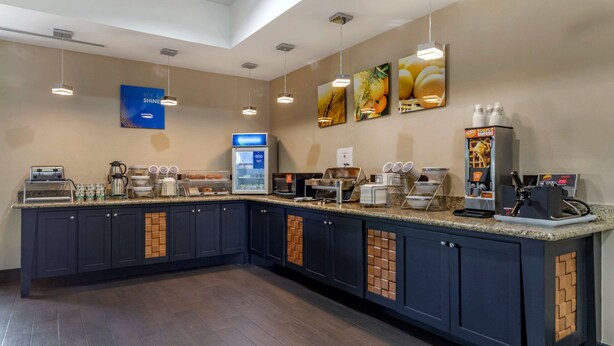 A modern kitchen area with a coffee station, a refrigerator, and a microwave.