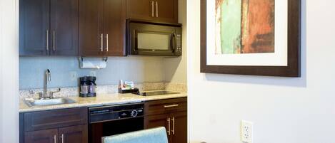 A kitchen with dark wooden cabinets, a built-in microwave, a coffee maker, and a telephone on the counter.