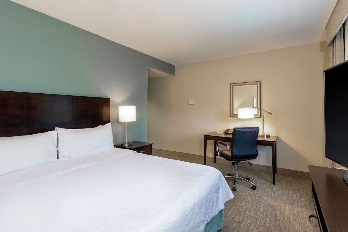 A hotel room with a bed, desk, chair, and a television.