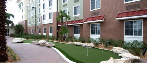 A hotel with a brick facade, multiple windows, and a landscaped area with artificial turf and rocks.