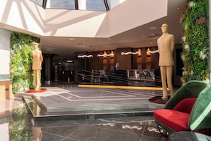 Un vestíbulo moderno con una escalera central, una recepción y un maniquí.