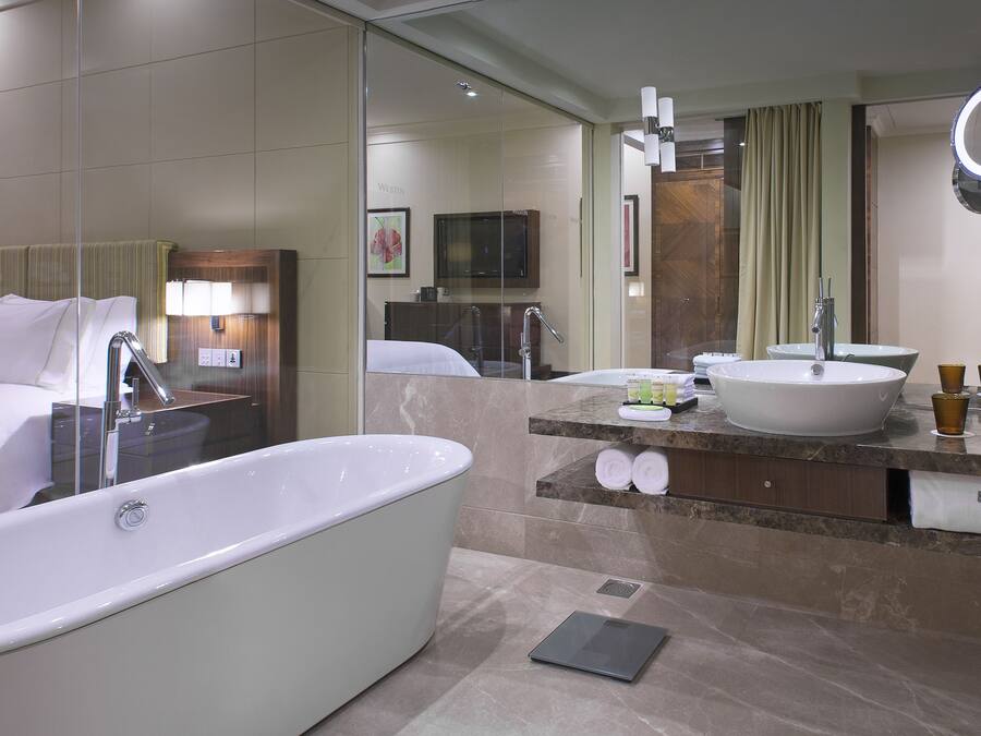 A modern bathroom with a large bathtub, a vanity with a sink, and a mirror.